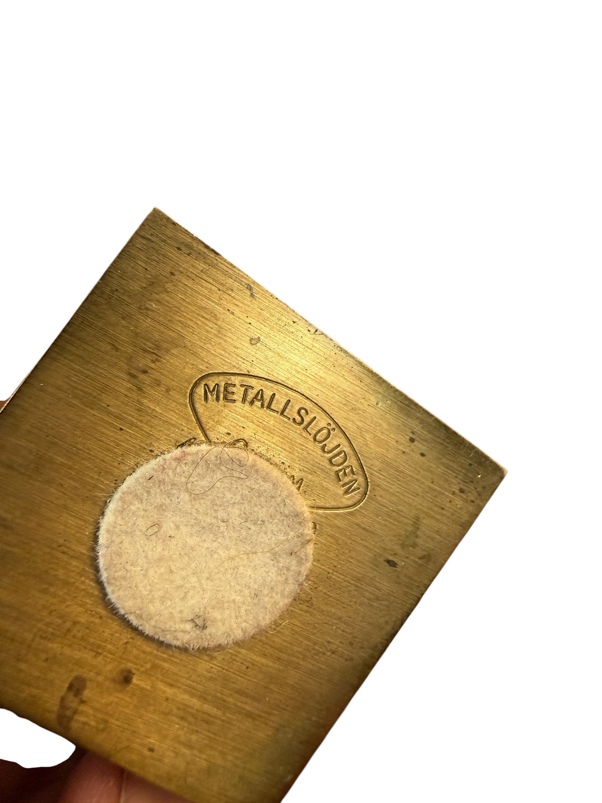 Undersida av Modighus.se ljusstake i mässing från Metallslöjden Gusum med stämpel och filtad bas