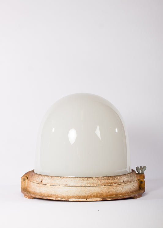 Stor industrilampa med välvd vit glaskupa och stomme i gjutjärn
