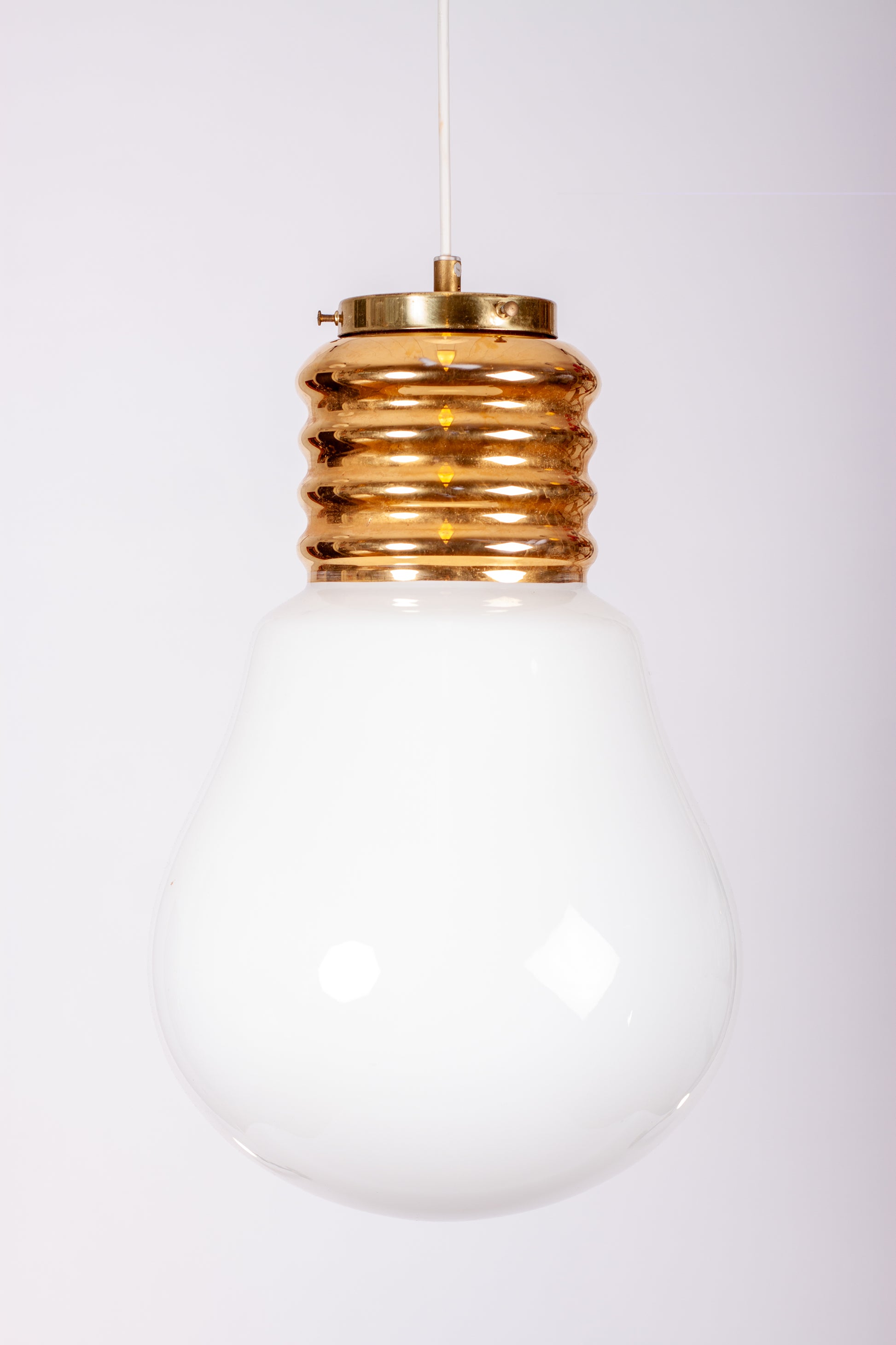 Dekorativ taklampa formad som en stor glödlampa i vitt glas med gulddetaljer och mässingssockel, 1970-tal
