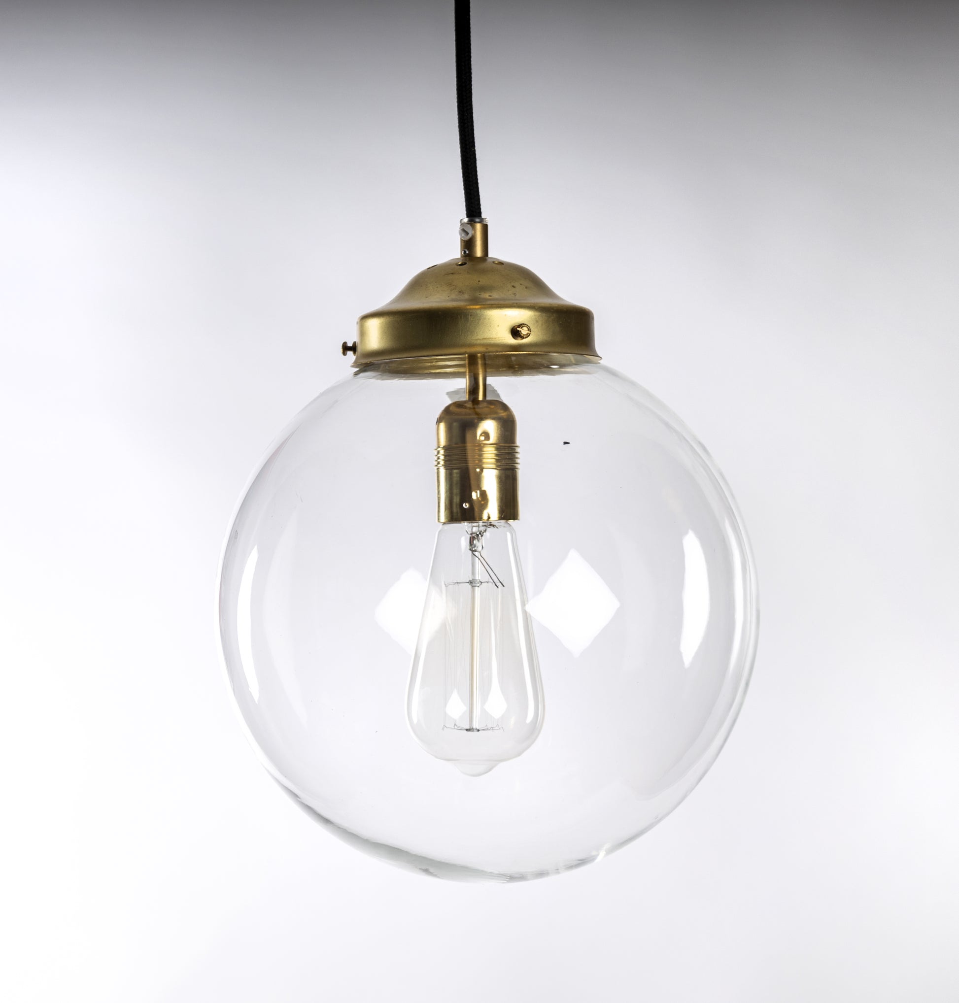 Taklampa med klarglas glob, mässingsfäste och svart rund textilkabel, passar koltrådslampa, 1950-tal
