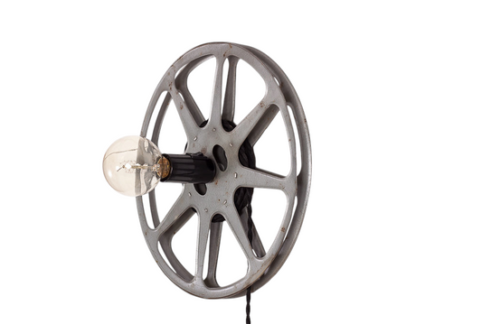 Unik vägglampa formad som en gammal filmrulle med svart tvinnad tygkabel.
