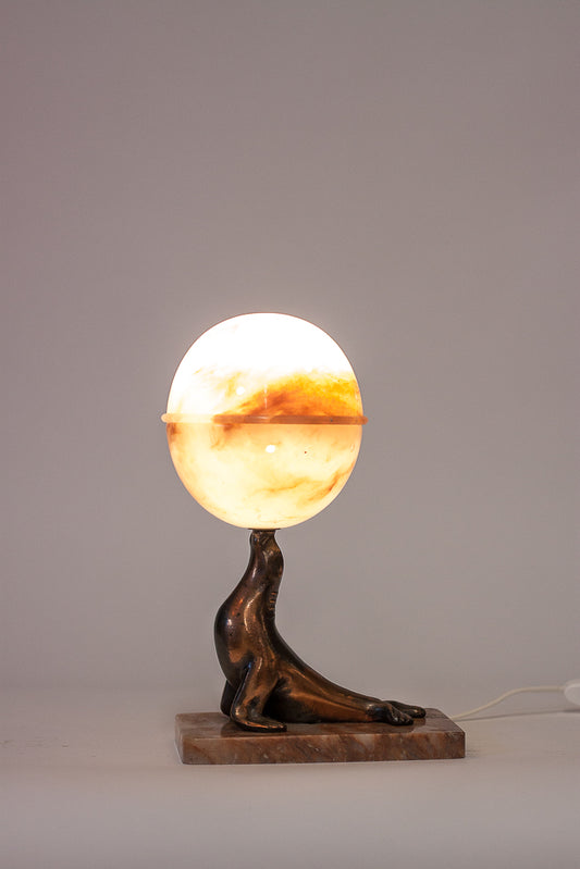 Art Deco bordslampa från 1920-talet med fot i brons och mässing, monterad med glob i vit alabaster och sjölejonsdekor.
