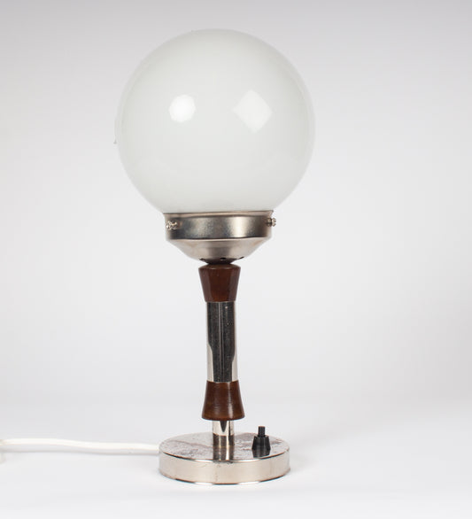 Bordslampa med fot i metall och trä från tidigt 1900-tal, monterad med vit glasglob. 
