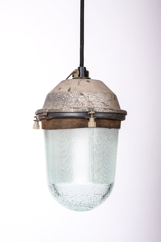 Rå industrilampa med härlig patina på fäste och tjockt glas, monterad med svart textilkabel. 
