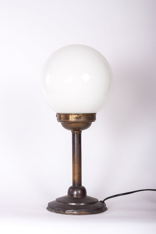 Klotlampa med fot i koppar och vit glasglob från tidigt 1900-tal. 
