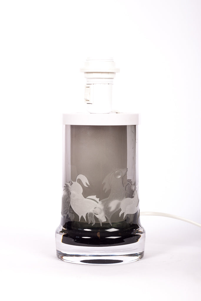 Bordslampa i röktonat glas från Kosta, designad av Ove Sandberg på 1960-talet. Slipade hästmotiv
