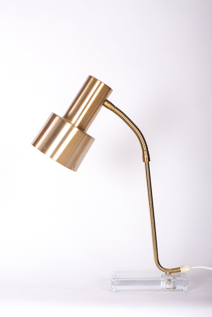 Stilren skrivbordslampa med glasfot och stomme i mässing
