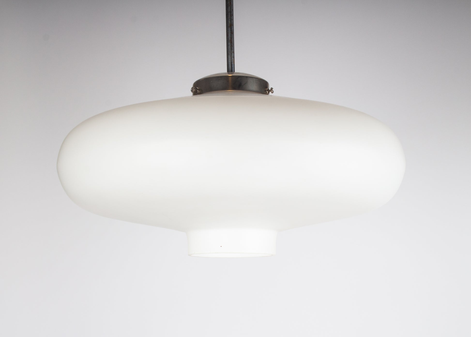 Taklampa i ufoform tillverkad av vitt glas.
