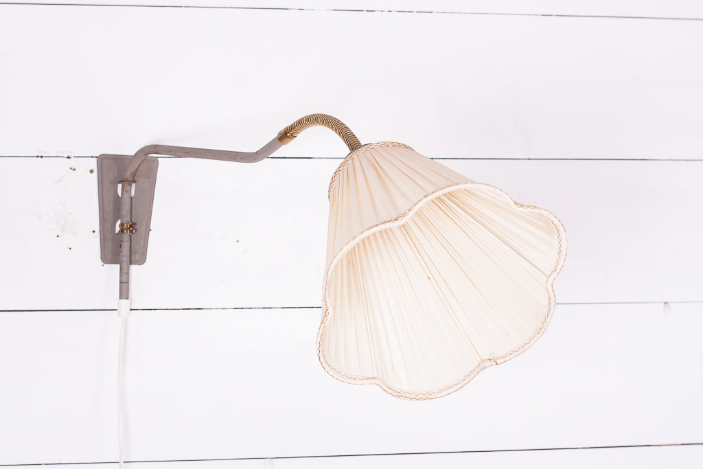 Vägglampa med gråmålad stomme och detaljer i mässing
